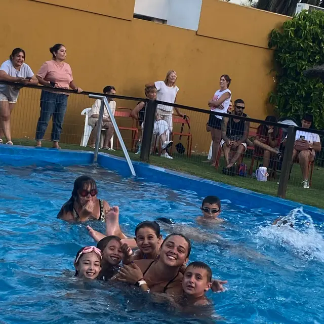 Una profe con un grupo de chicos en la pileta del club